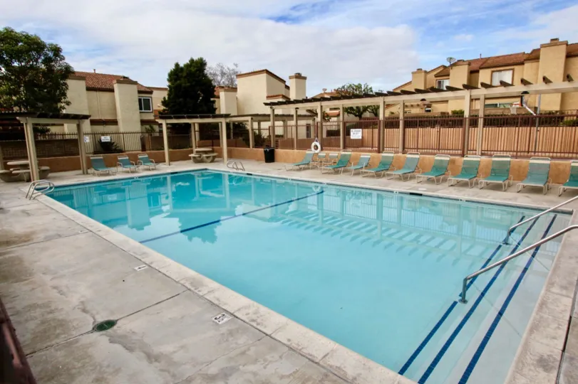 A pool in the Mark III Townhomes community with deck chairs on a cloudy day.