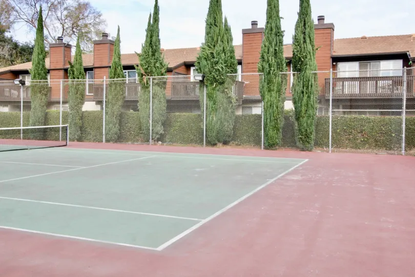 Tennis courts in the Mark III Townhomes with a metal fence on a cloudy day.