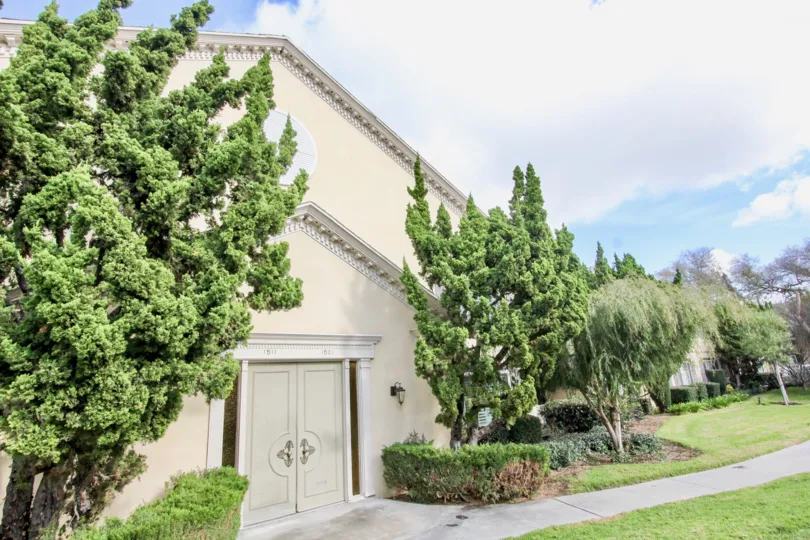 A white house with large trees around it at meredith manor community in fullerton, california.