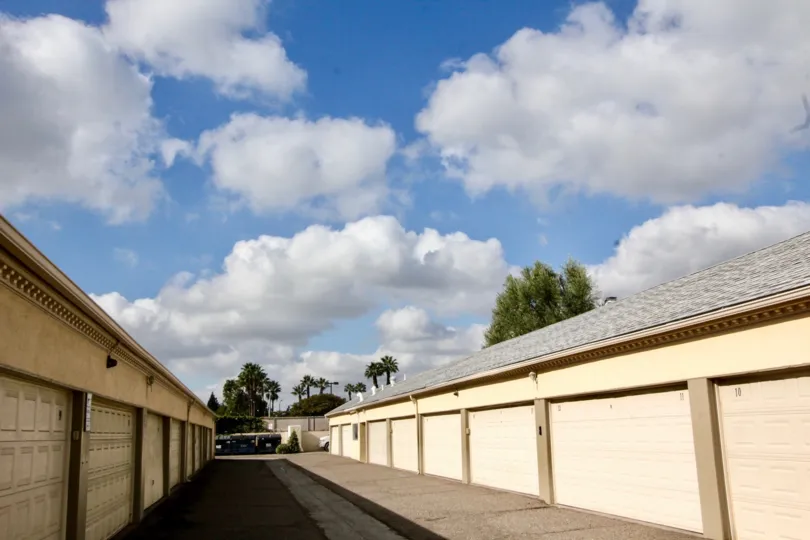 Partially cloudy day with sun peaking through shining down on rows of garage units in Meredith Manor community.