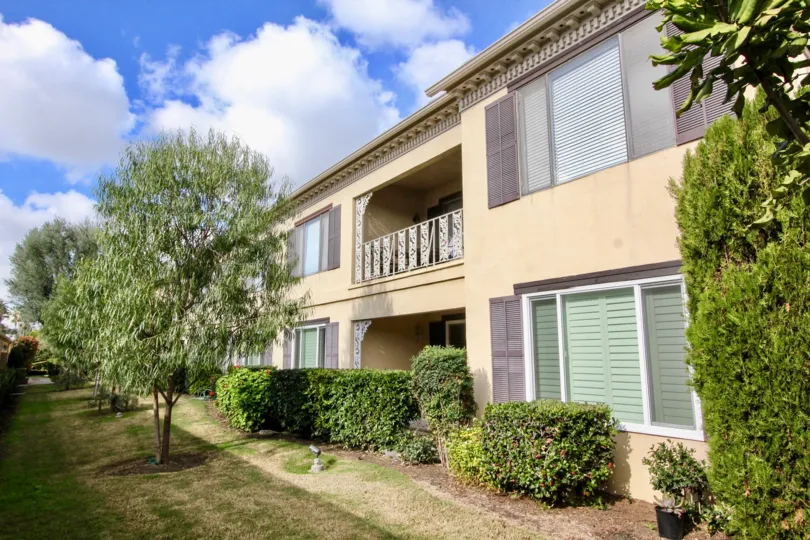 A building with two floor and big windows and also having balcony in front of trees at the morning time.