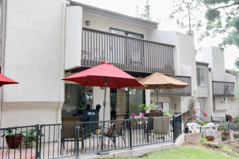 Two story white town homes with chairs and tables in park vista community in fullerton, california.