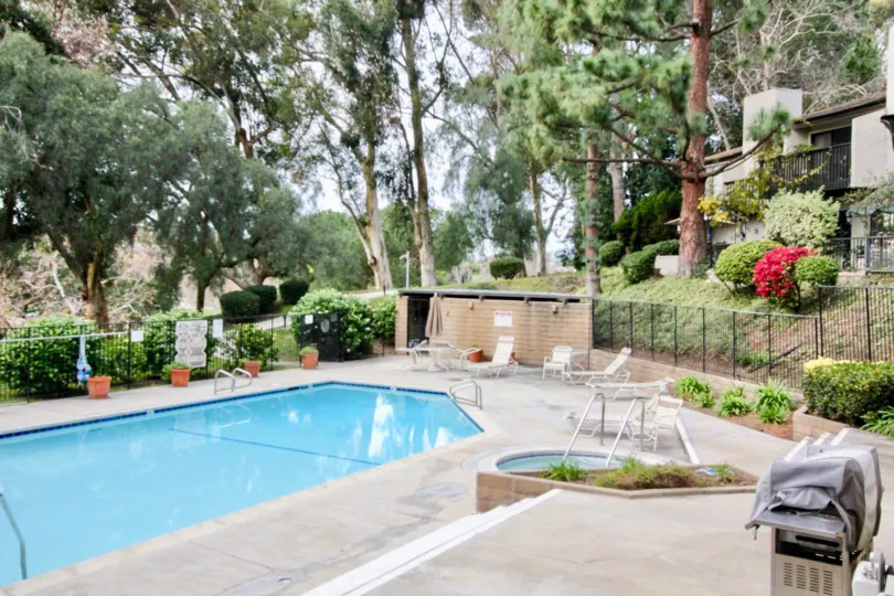Pool in Park Vista with a hot tubs and deck chairs surrounded by a fence.