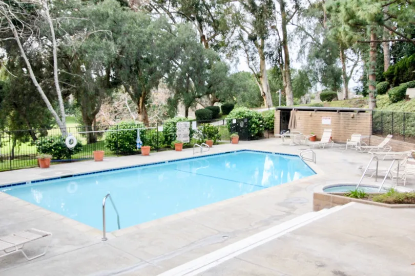 Private gated swimming pool with chaise lounges and whirlpool spa, surrounded by plenty of foliage in Park Vista community, Fullerton, CA.