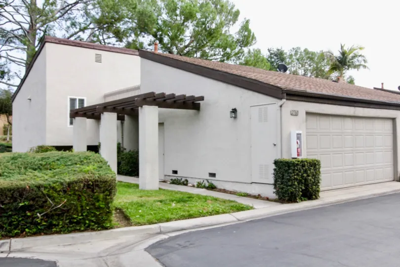 A white building and garage with bushes at park vista community in fullerton, california.