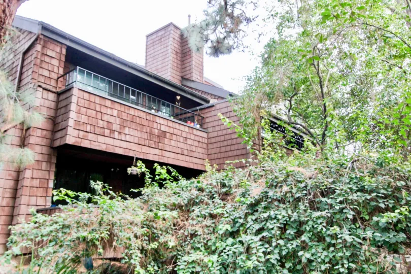 A beautiful red house in the Quail Ridge with big trees, glass windows and shrubs.
