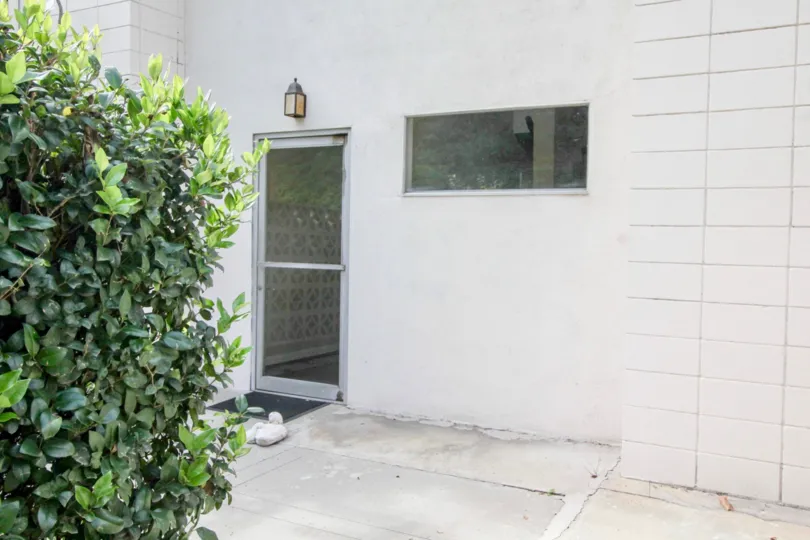 Glass door to a white Shadow Lane buidling next to bushes.