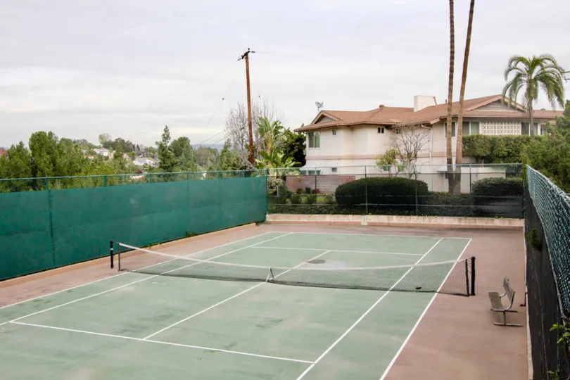 Tennis Court in Shadow Lane with a net and bench on a cloudy day.