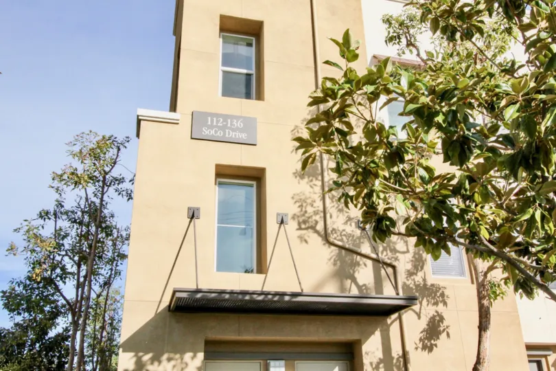 A tall tan building with 112-136 soco drive address on it at soco walk community in fullerton, california.