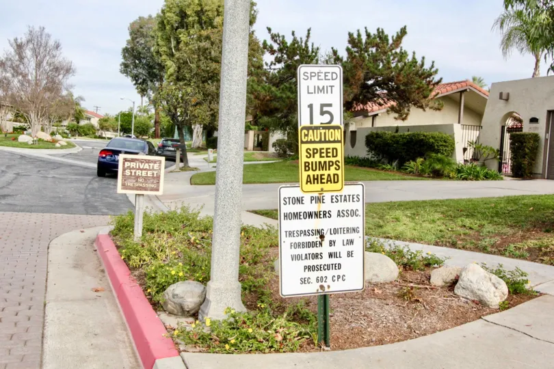 Three notices are attached in a single lamp near the light lamp placed between bushes and rocks in Stone Pine Estates