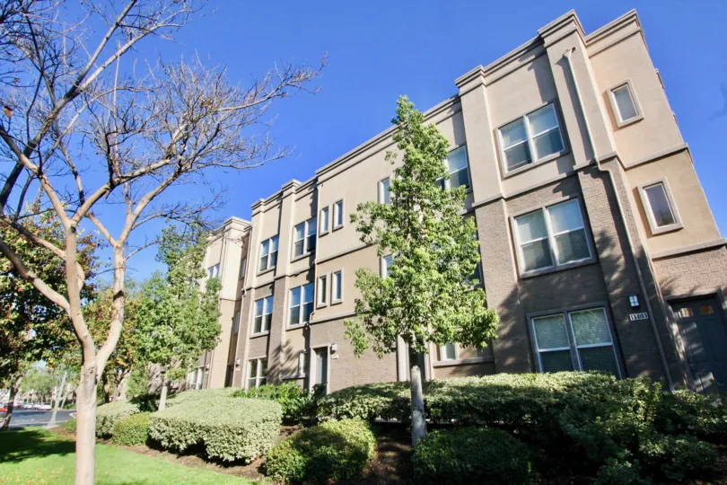 Large multi level building that is tan in color with lots of trees in the front located in the Studio walk community.