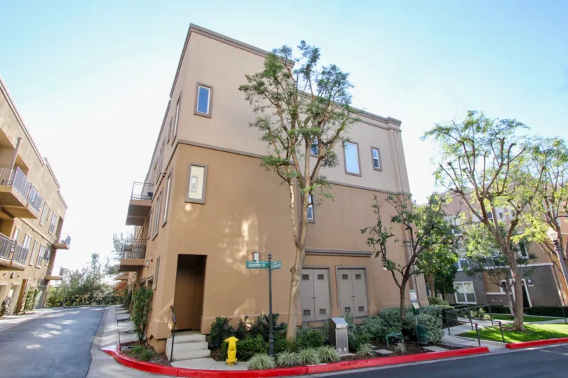 A Studio Walk apartment complex with trees and bushes on a sunny day.