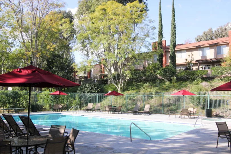 A gorgeous blue pool lined with outdoor furniture inside the Sunny Ridge Townhomesin Fullterton CA