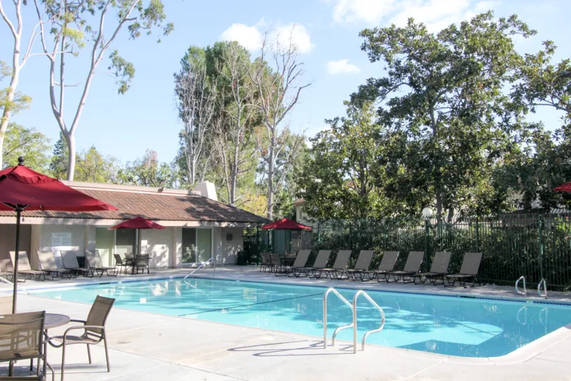 A sunny pool lined with lounge chair located in Sunny Ridge Townhomes community.