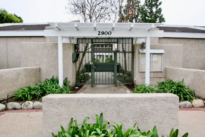 White and black gate with plants along the walls in the arbor community in fullerton, california.