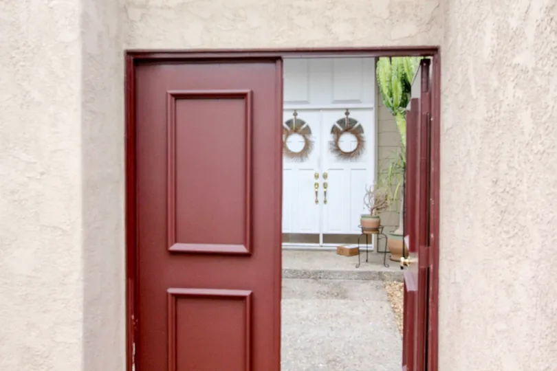 A open red door to The Arbor with potted plants inside.