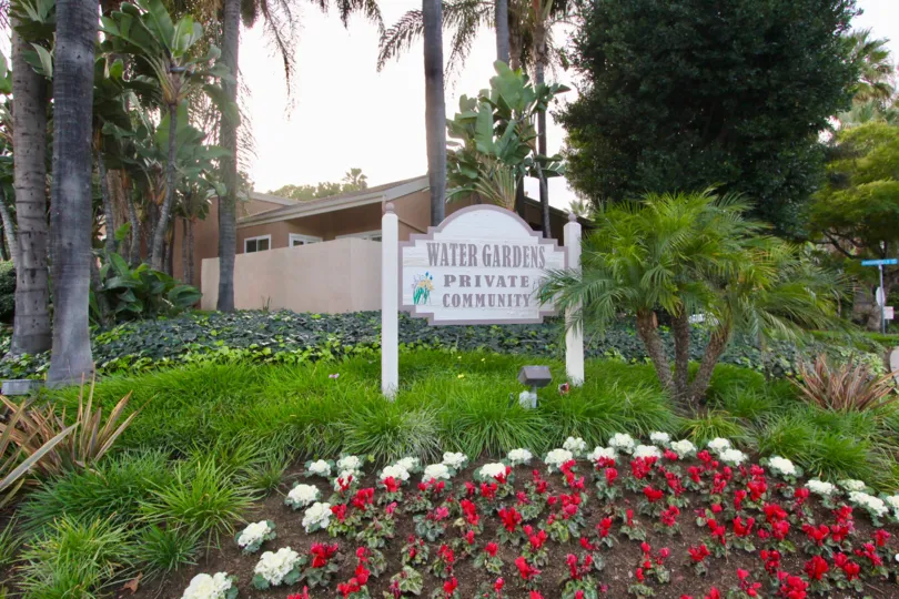 Entrance sign in the middle of well maintain flower and tree area naming the community Water Gardens.