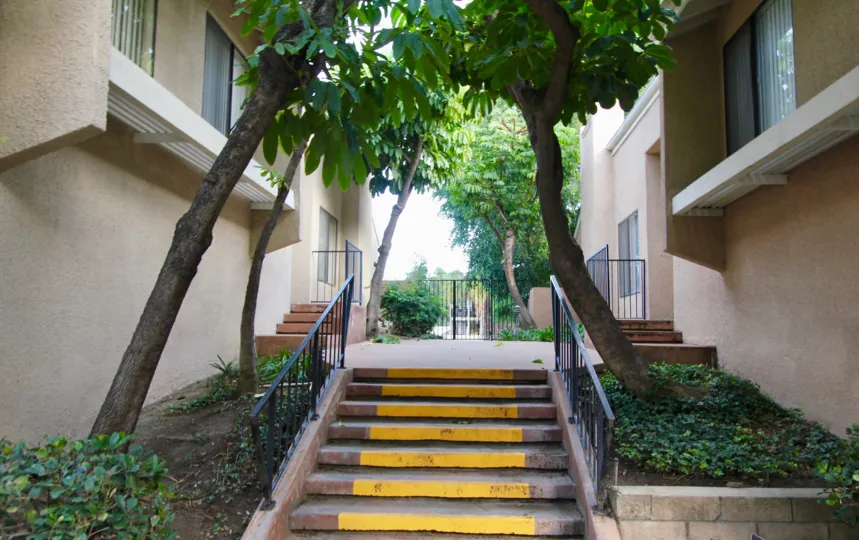 A short set of stairs with yellow stripes painted across each step in Water Gardens in Fullerton CA
