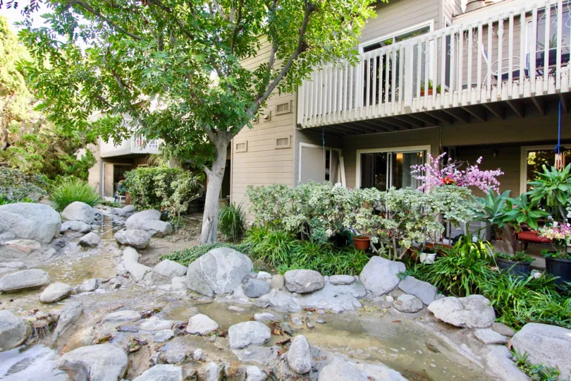The sun is out at the Cobblestone Creek in Garden Grove, California where the creek is flowing through rocks.