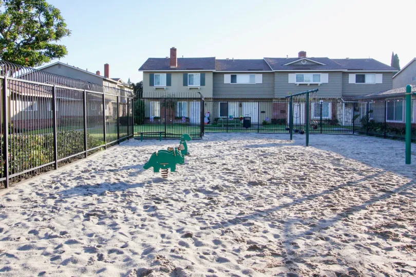 A beautiful gated community that has a sand covered and cozy playground for the children as well.