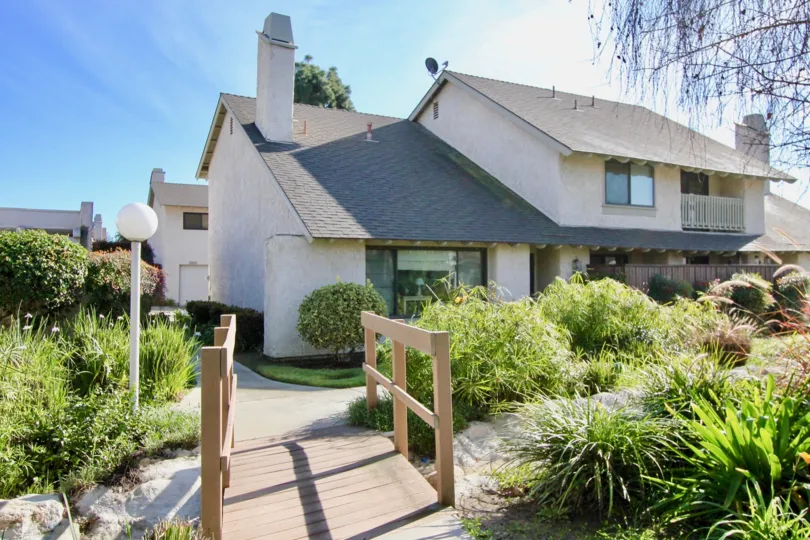 A home in the Hidden Village community of Garden Grove, with a landscaped yard and wooden footbridge.