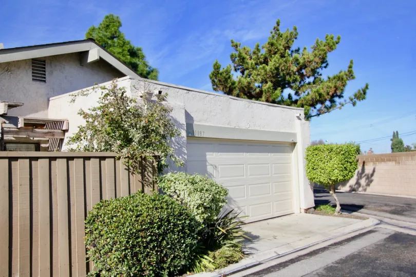 garage view of a house with brown fence on the sire and bushes around