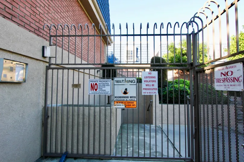 An ornate fence with warning signs at La Palma Hills, in Garden Grove, California.
