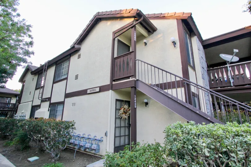 THIS IMAGE VIEWS THE VILLAS THAT HAS SURROUNDED BY THE PLANTS, TREES AND SHOWS THE DISH, NUMBER AND NAME BOARD ON THE WALL IN THE CITY OF GARDEN GROVE