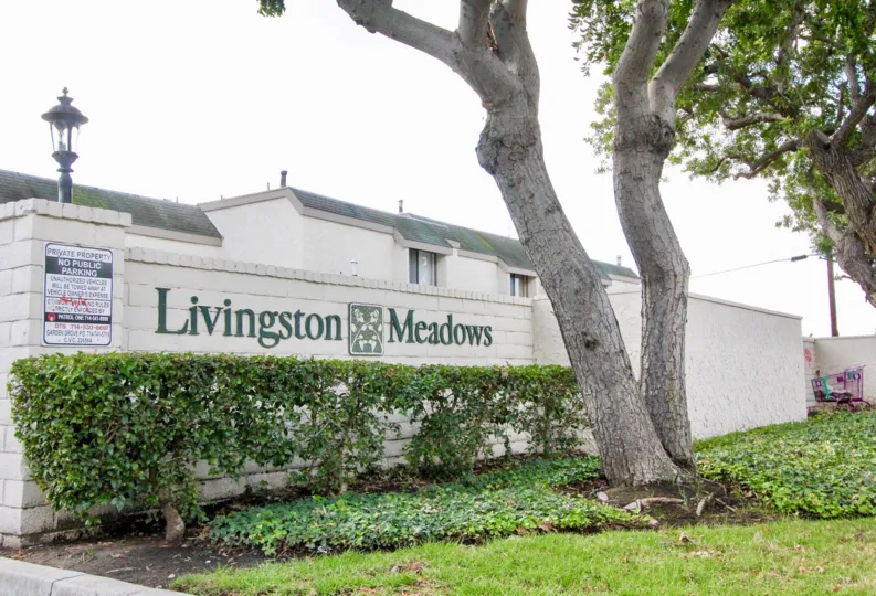 THE HOME IN THE LIVINGSTON MEADOWS WITH THE NAME WALL, TREES, LAWN, PLANTS
