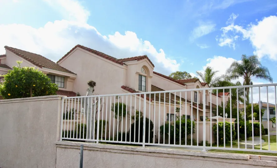THIS PICTURE VIEWS THE APARTMENTS THAT HAS SURROUNDED WALLS, SHOWS THE BEAUTIFUL LAWN, PLANTS, TREES, ARE PLACED IN THE CITY OF GARDEN GROVE