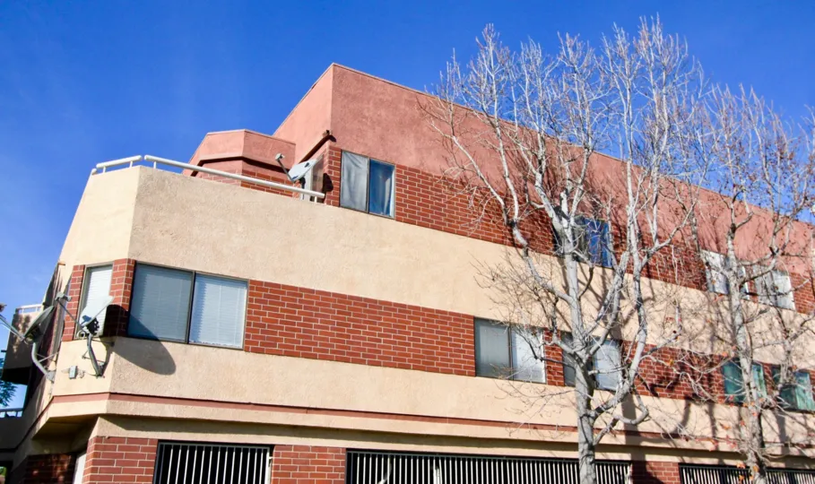 THIS SHOWS THE LARGE HOUSE THAT LOOKS BRICK RED IN COLOUR AND HAS THE DISHES ON EACH FLOOR AND HAS THE TREES IN THE CITY OF GARDEN GROVE