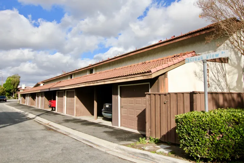 THIS SHOWS THE CAR SHEDS WITH CAR, ROAD WAY, NEARBY PLANTS, TREES ARE THERE IN THE CITY OF GARDEN GROVE