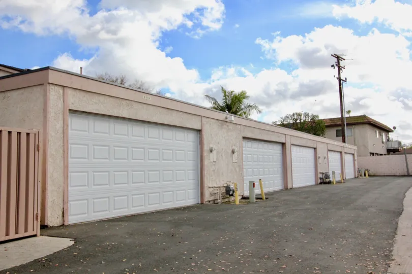 A run down road in an alleyway lined with clean looking garages at New Brookdale in Garden Grove CA