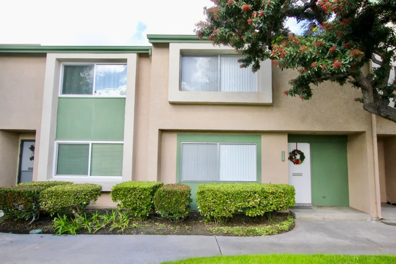THIS SHOWS THE FRONT OF THE HOUSE WHICH IS CLOSED WITH WOODEN DOOR, AND GLASS WINDOWS AND SURROUND BY THE PLANTS WHICH IS PLACED IN THE COMMUNITY OF PACIFIC GARDENS