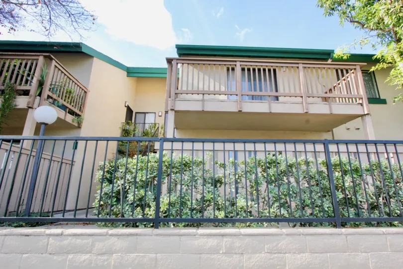 a housing view with a fence in front with a small lamp and balconies on second floor