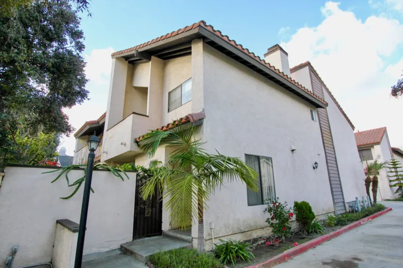 THIS IMAGE SHOWS THE BEAUTIFUL HOUSE THAT HAVE THE NIGHT LAMB, PLANTS, AND THE TREES SURROUNDED BY THE ROAD IN THE CITY OF GARDEN GROVE