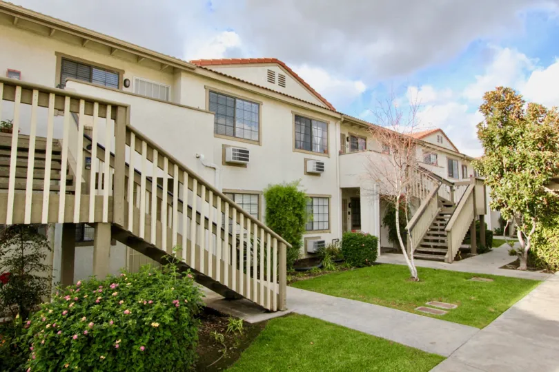 THE BUILDING IN THE SPRING GARDEN VILLAS WITH THE UPSTAIRS, LAWN, FLOWER PLANTS, TREES
