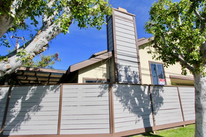 a sunny day in the stanford plaza with a building that has roofless in top and closed the gate