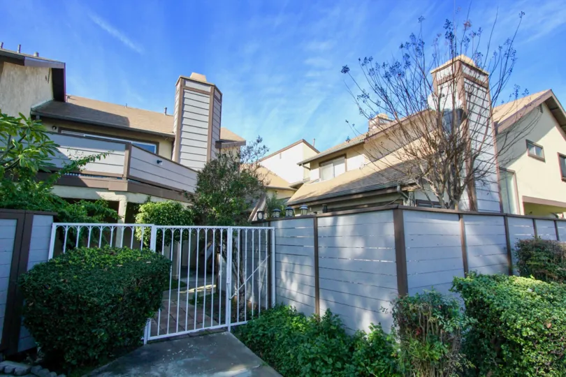 THIS IMAGE VIEWS THE FRONT OF BEAUTIFUL VILLA WITH PLANTED PLANTS, TREES, GATES, WHICH IS IN THE CITY OF GARDEN GROVE
