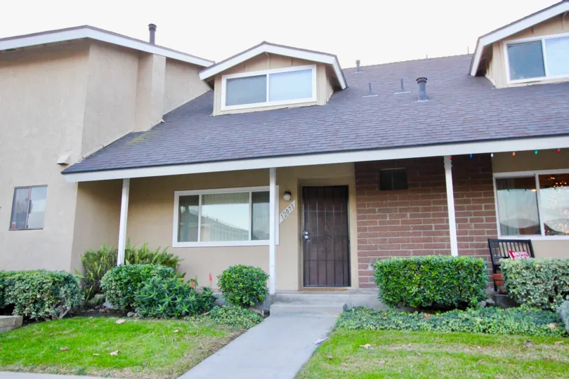 Brick and stucco home with dormers and iron work storm door at Stonegate in Garden Grove, CA