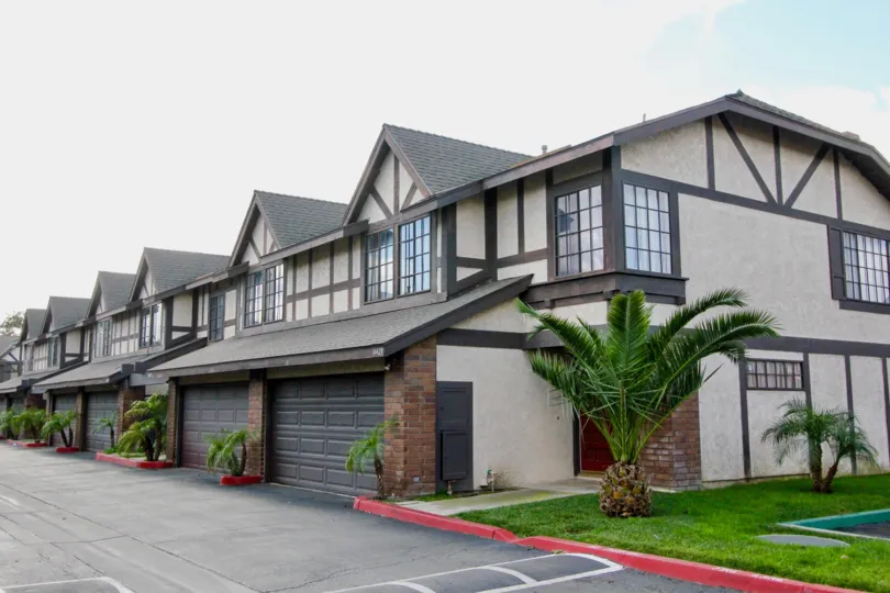 A set of Northern-European style homes with double garages and palm trees located in the Tudor Estates community in Garden Grove, California.
