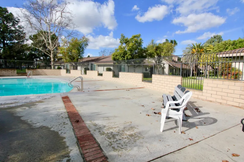 Nice day to hang by the pool on lawn chairs and observe the surrounding apartment complex, which is decorated with trees and blue sky.