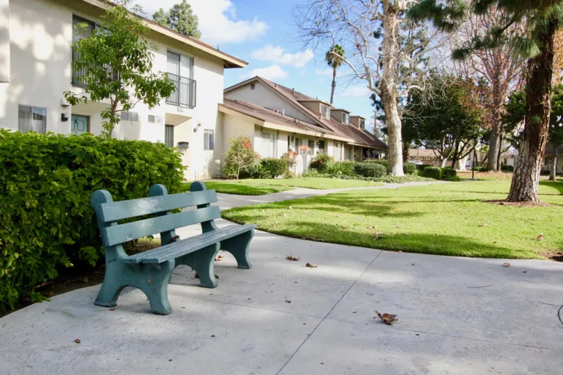 THIS IMAGE REPRESENTS APARTMENTS WHICH HAS THE BEAUTIFUL LAWN, LOT OF TREES, PLANTS WITH FLOWERS ARE SHOWN IN THE CITY OF GARDEN GROVE