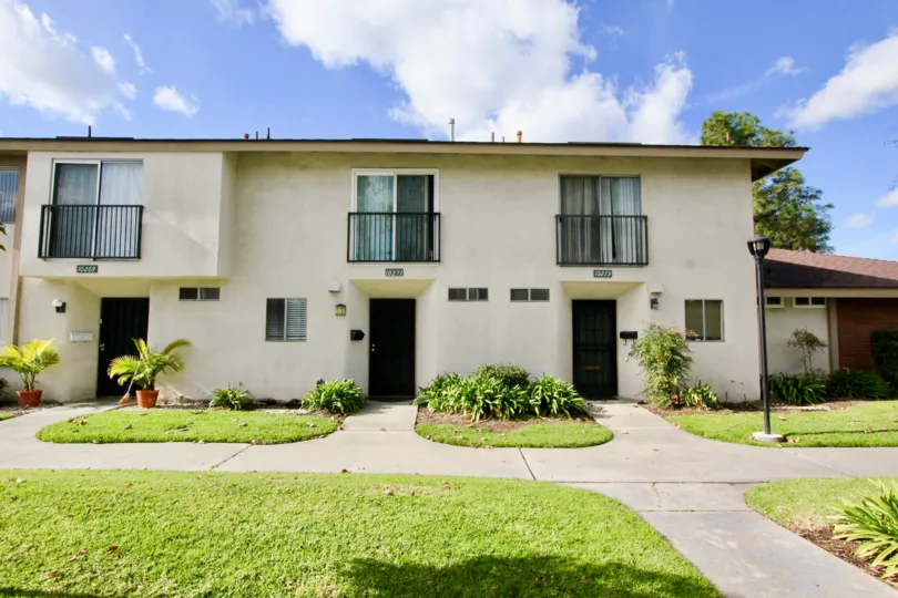 Three doors to a cream colored apartment building in Westbrook, found in Garden Grove, California