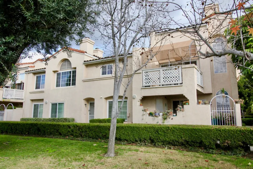 Front to the house in Yorkshire Townhomes has dry tree and fresh trees with bushes and meadows