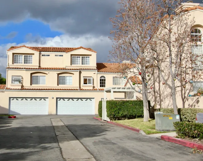 THIS SHOWS THE BEAUTIFUL VILLA THAT HAS THE PATHWAY TO THE INSIDE AND GLASS WINDOWS, PLANTS AND TREES ARE SHOWN IN THE CITY OF GARDEN GROVE