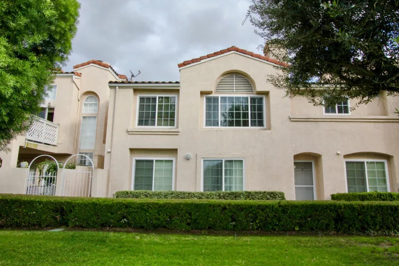 a mansion with cream colour and elegant design and maintained greenery around