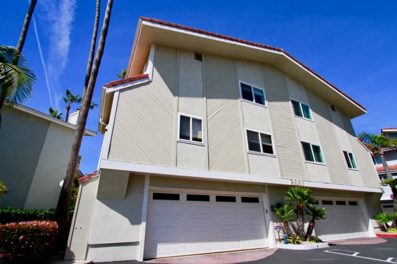 Bayport apartment with garages and palm trees on a sunny day.