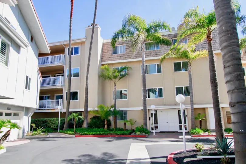 A four story condominium structure with many windows sits behind a driveway at Bayport in Huntington Beach CA