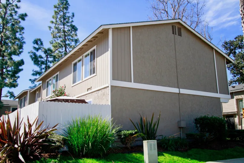 THE BUILDING WITH MORE WINDOWS AND TWO FLOOR ONE CABLE ALSO AVAILABLE AT THE SIDE OF THE HOUSE WALL SOME PLANTS NEAR TO THE HOUSE AND THE SKY LOOKING LIKE BLUE.